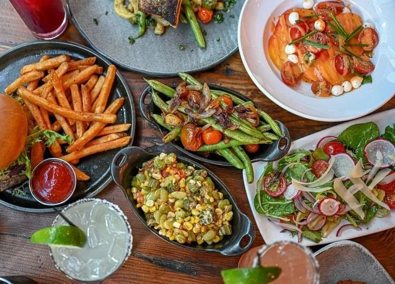 Top-down view of a rustic wooden table laden with diverse food and drinks.