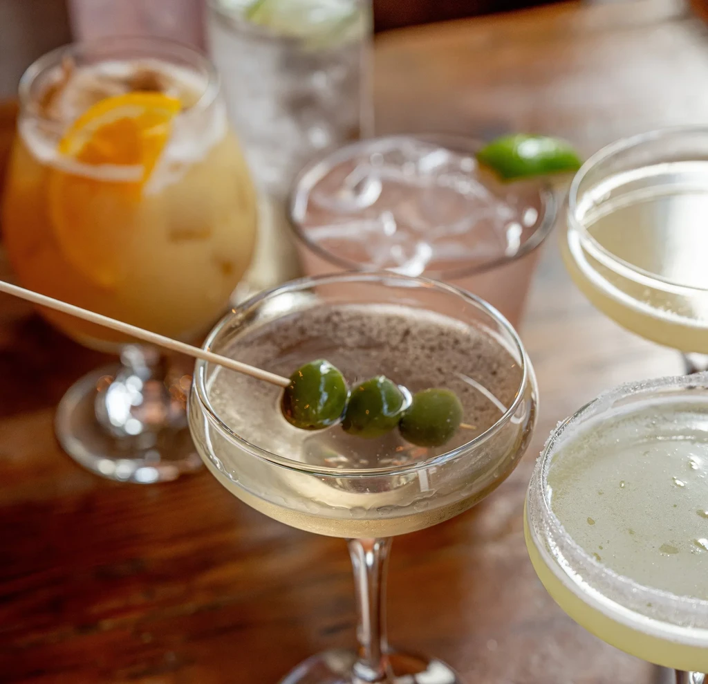 Close-up of a martini and other drinks on a wooden table.
