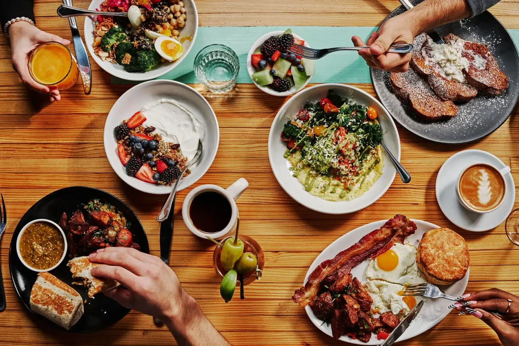 High-angle view of a diverse breakfast and brunch spread with hands.