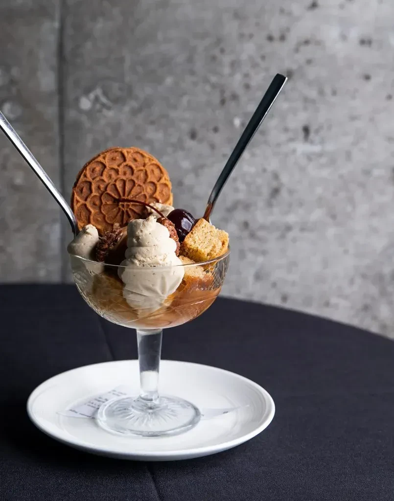 Layered dessert in glass with waffle cookie and spoons.
