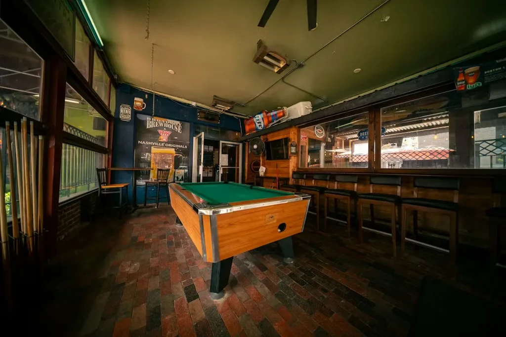A casual bar interior with a green pool table and wood bar.