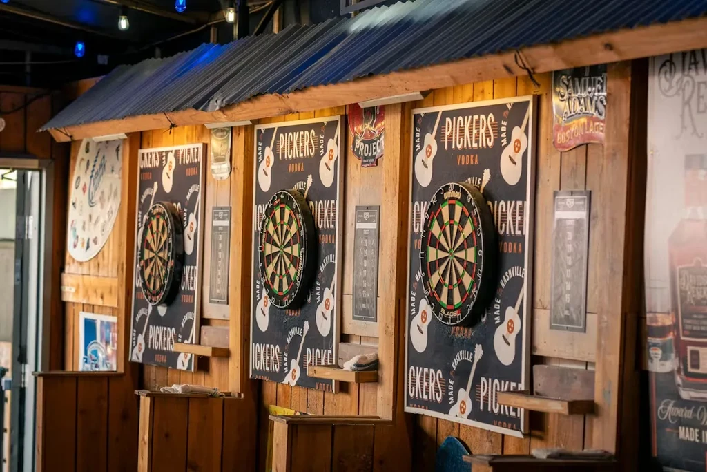 Three dartboards on a rustic wooden wall with vodka posters.