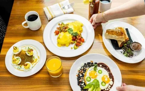Overhead view of a restaurant table with several brunch dishes and beverages.