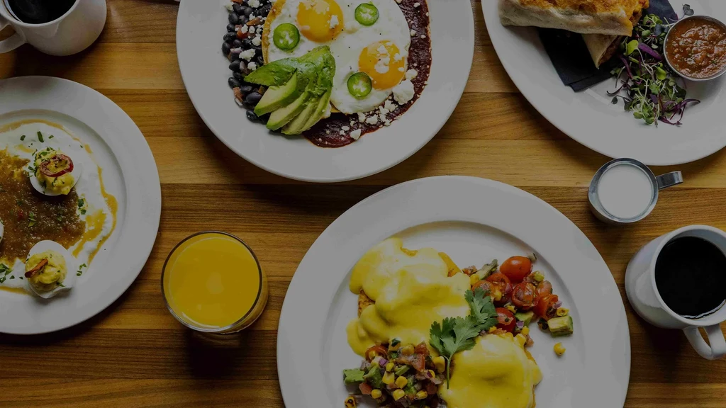 Overhead shot of various breakfast and brunch dishes on a wooden table.