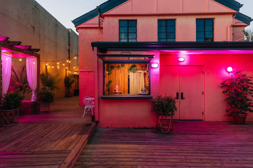 Vibrant pink restaurant building and patio illuminated at dusk, no people.