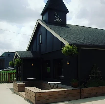 Dark building exterior with falcon logo steeple and patio seating.