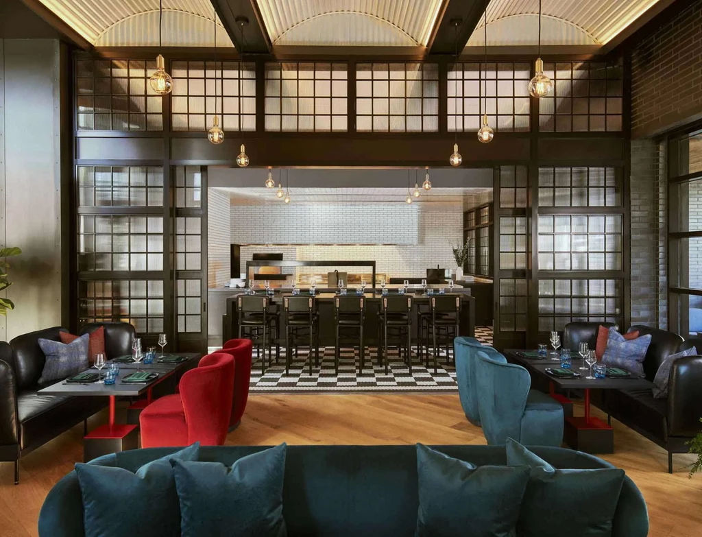 Empty modern restaurant interior with bar, open kitchen, and diverse seating.