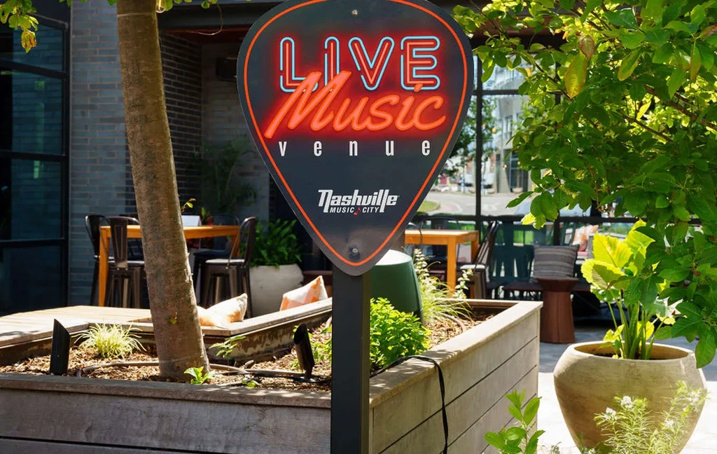 Neon guitar pick sign for a Nashville live music venue patio.