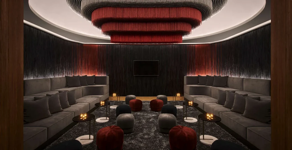 Dark, modern lounge with fringe decor, tiered seating, and warm lighting.