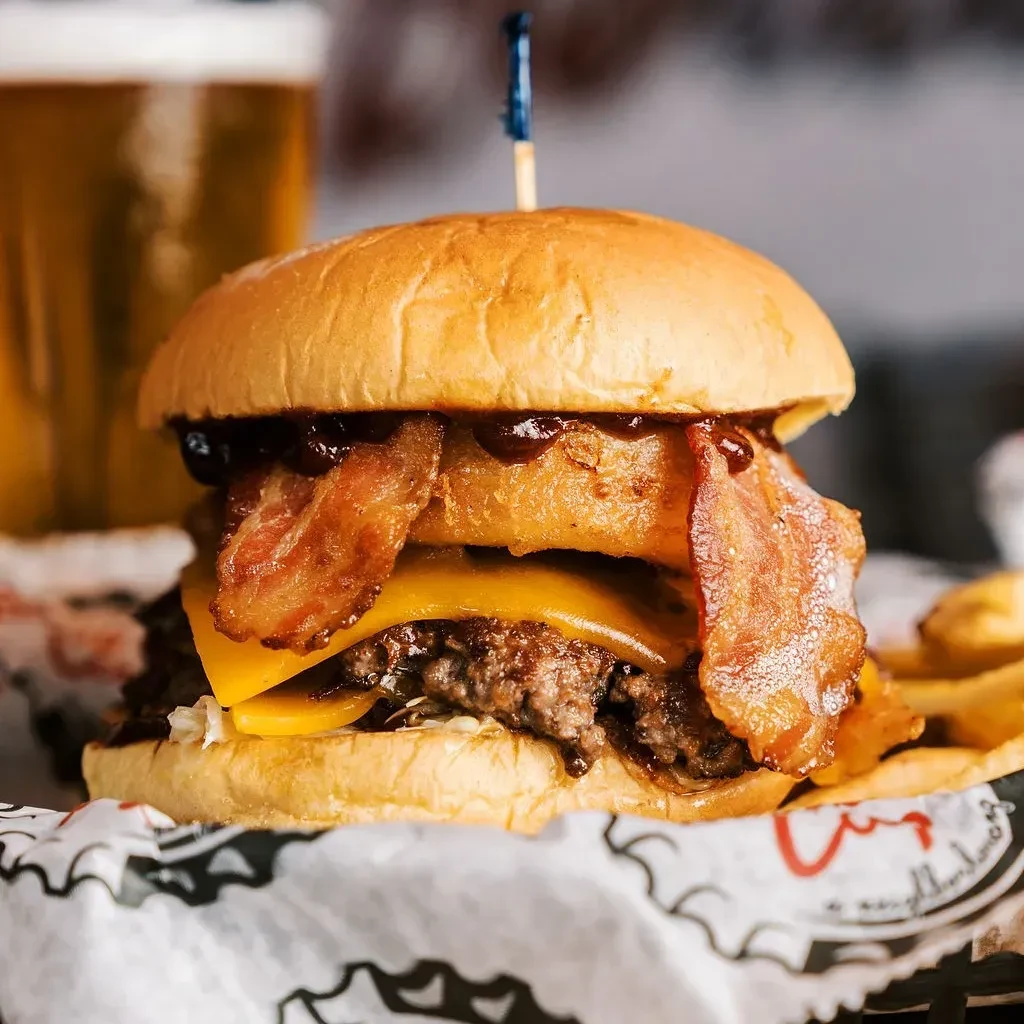 Gourmet burger with beef patty, melted cheddar, bacon, and onion ring.