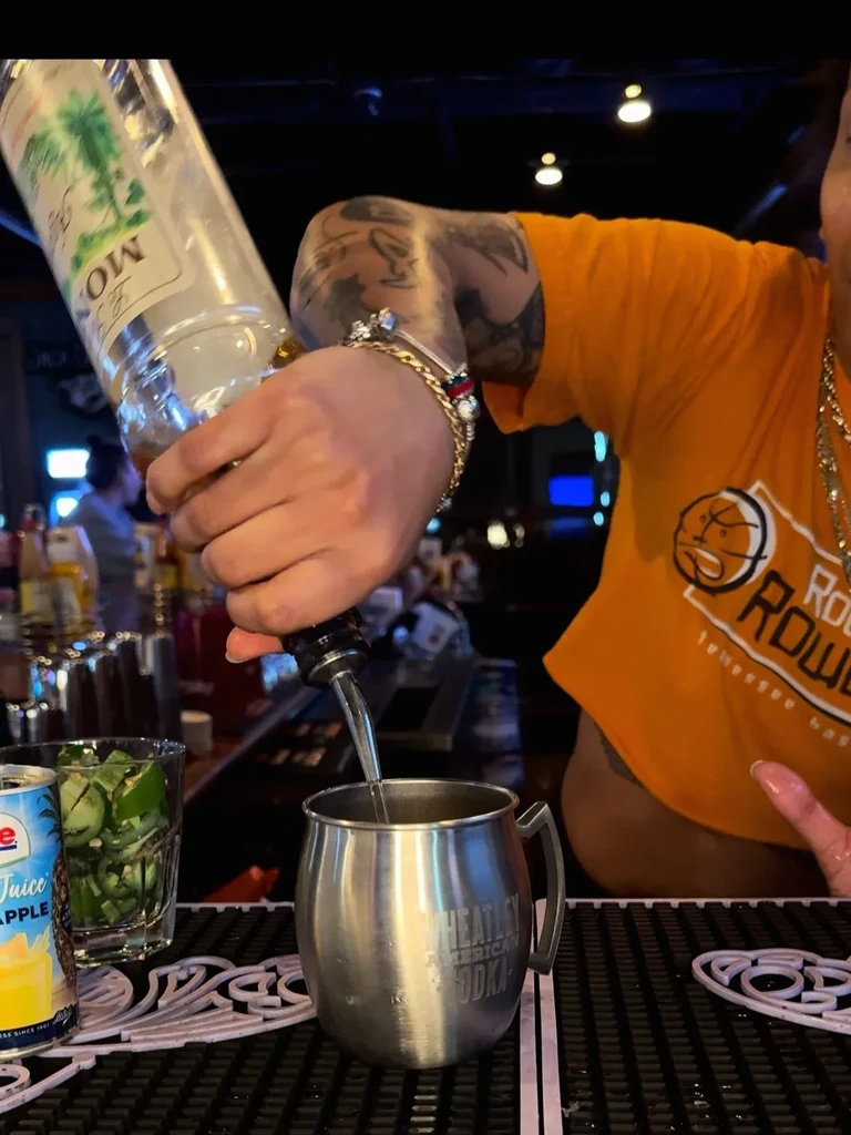 Tattooed hands pour Montezuma into a Wheatley American Vodka mug.