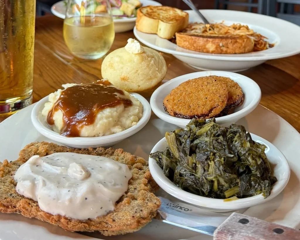 Chicken fried steak with gravy, mashed potatoes, fried green tomatoes, and collard greens.