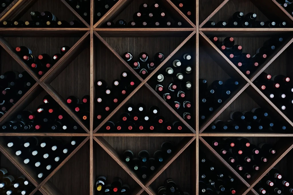 Dark-stained wooden wine rack filled with numerous organized wine bottles.