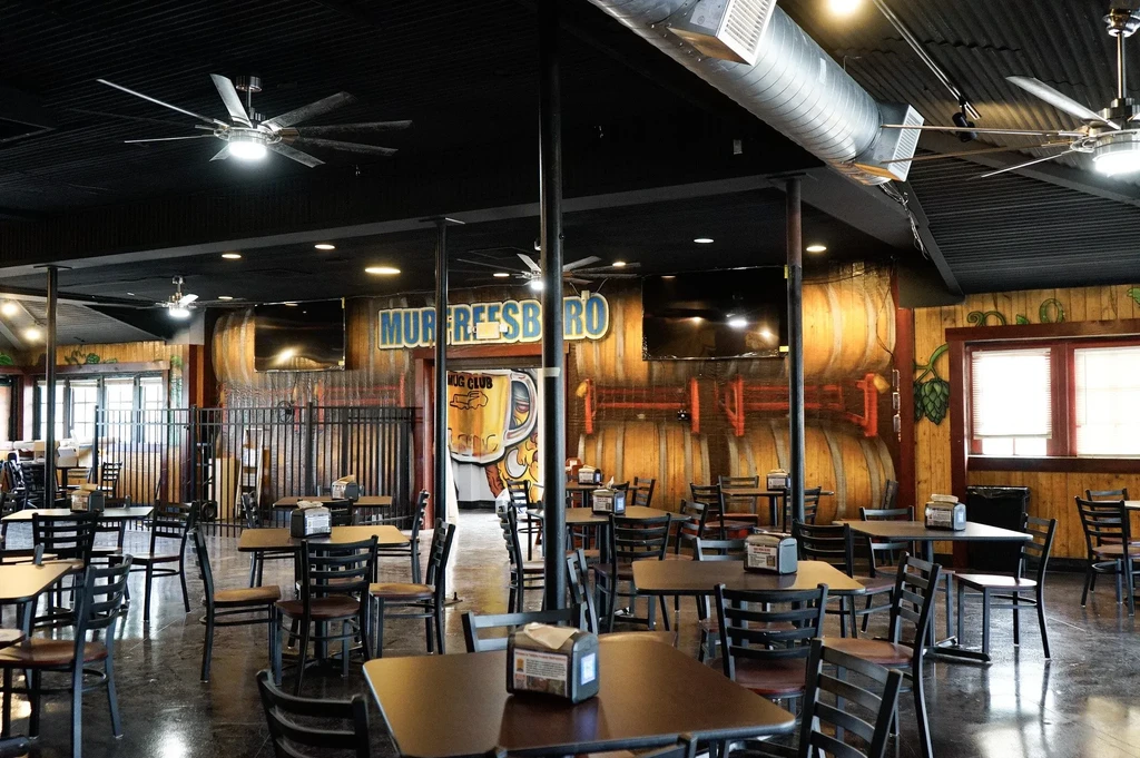 Empty brewpub interior with a beer barrel mural and industrial decor.