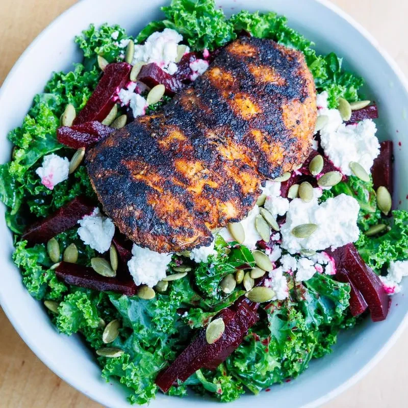 Overhead grilled chicken/fish salad with kale, beets, cheese, pumpkin seeds.