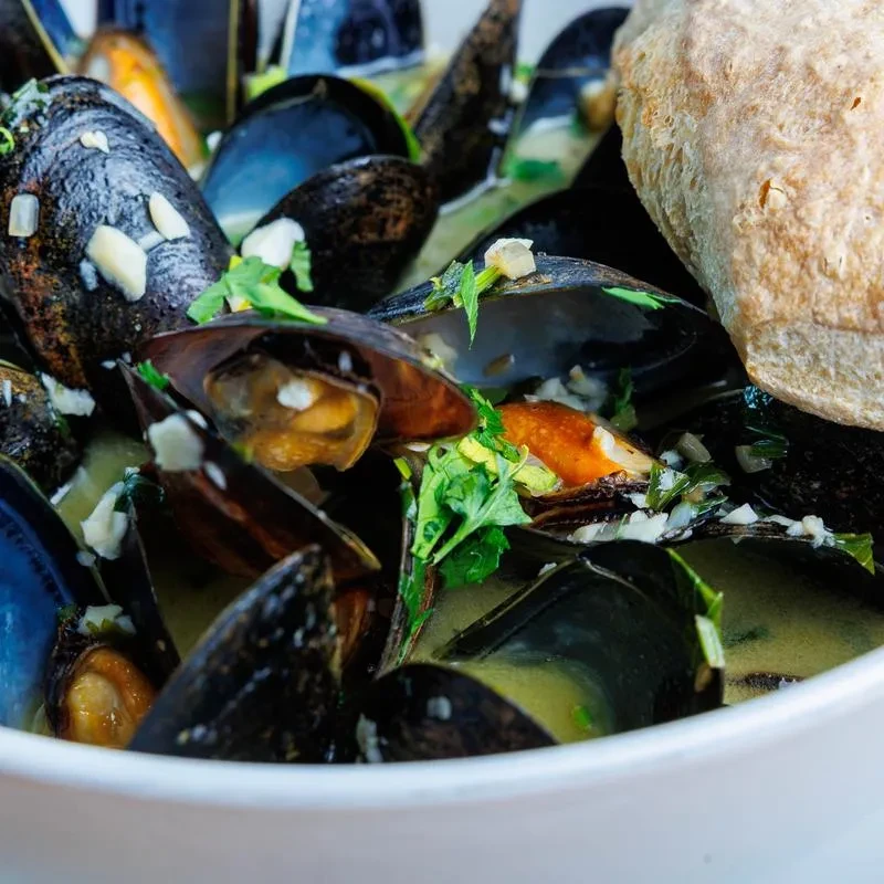 Steamed mussels in creamy broth with garlic, herbs, and baguette.