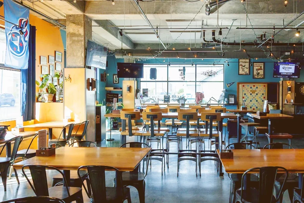 Vibrant industrial-chic restaurant interior with diverse seating and cozy lighting.