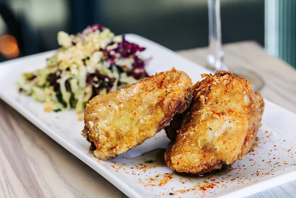 Two golden, crispy, seasoned fried food pieces on a white plate.
