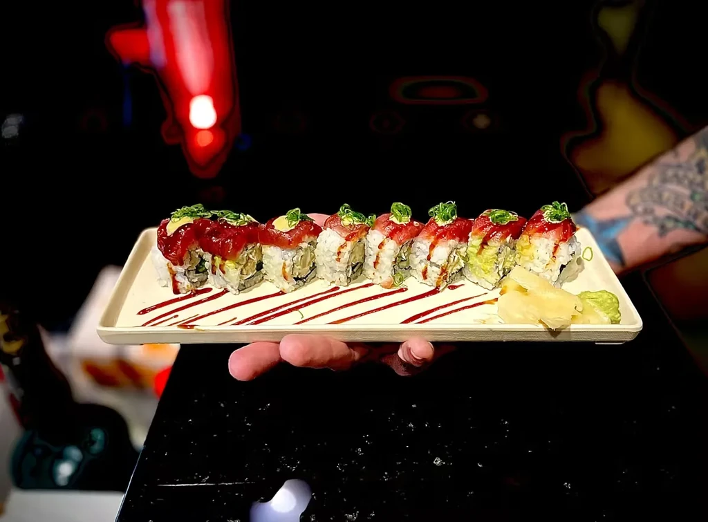 Eight tuna sushi rolls with ginger, wasabi, and sauce on a plate.