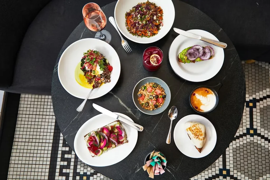 Round marble table with colorful healthy meals, drinks, and dessert.