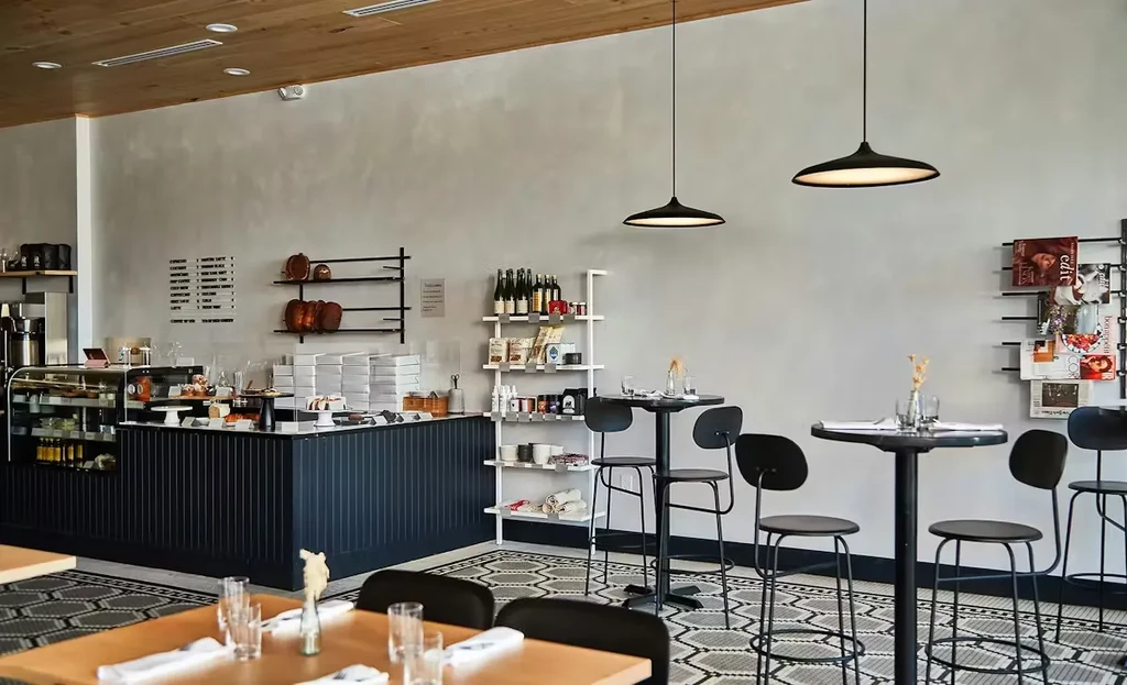 Wide shot of a modern, minimalist cafe with a counter and dining area.