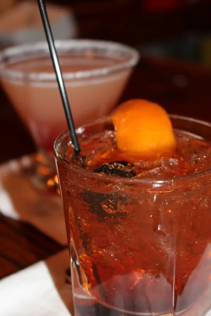 Two cocktails, an Old Fashioned and a martini, on a dimly lit bar.