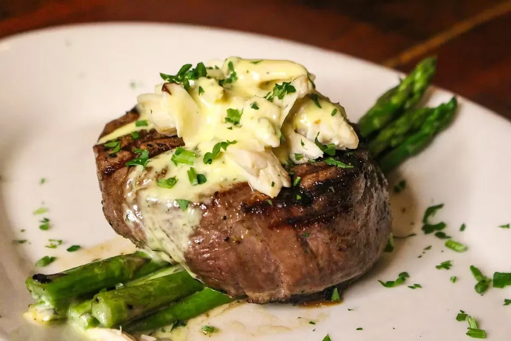 Grilled steak topped with white crab meat, creamy sauce, and asparagus.