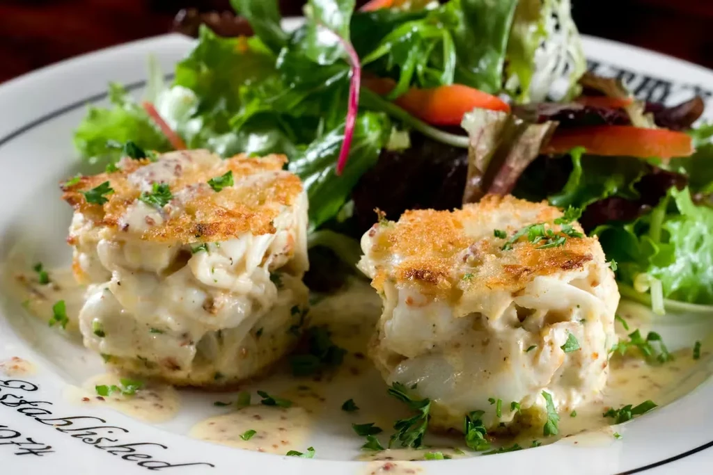 Golden-brown crab cakes with creamy mustard sauce and green salad.