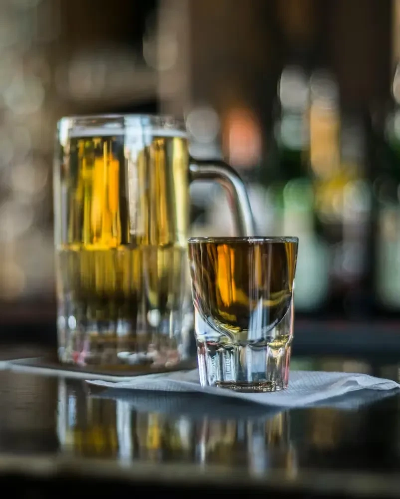A frothy mug and a shot glass filled with golden liquor.