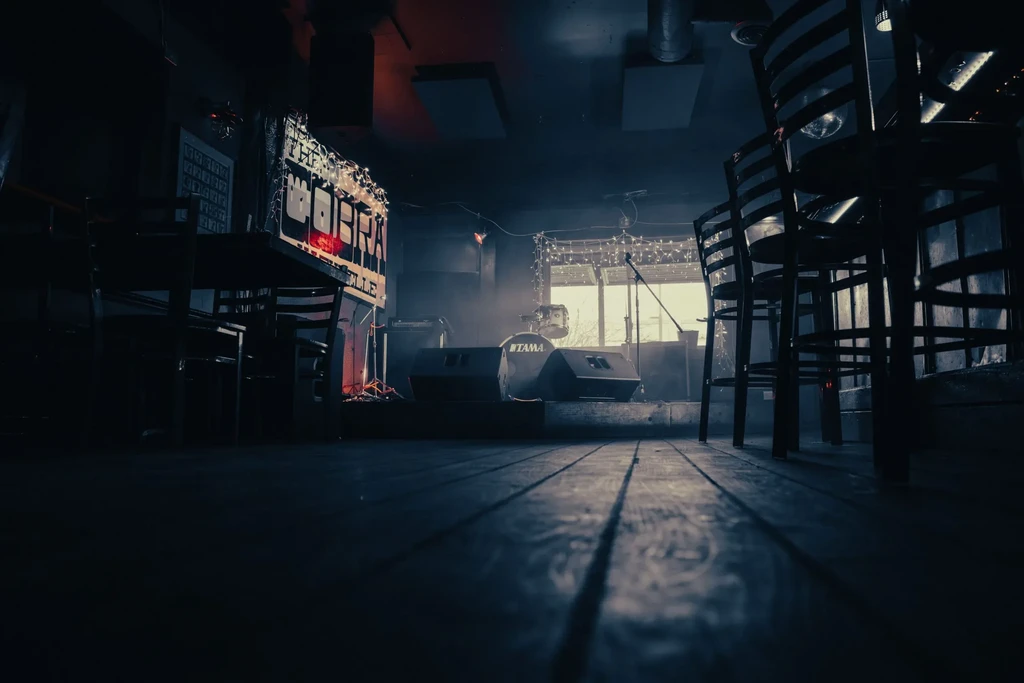 Dimly lit stage with drums, speakers, and 'THE COBRA VILLE' sign.