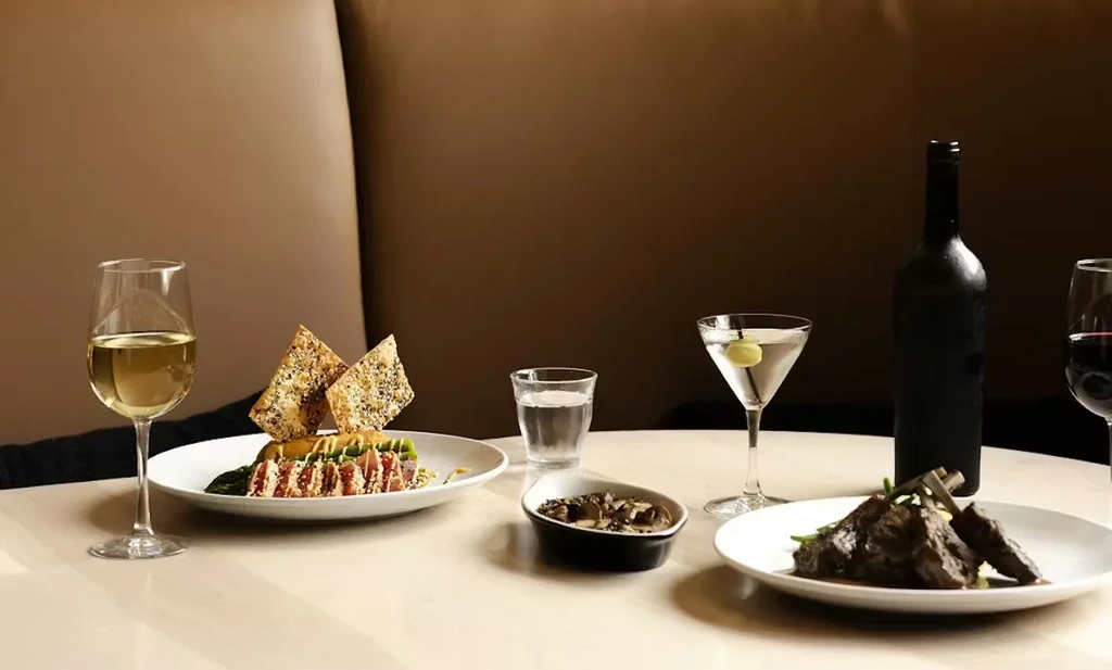 Upscale dining table displaying gourmet dishes, wines, water, and a martini.