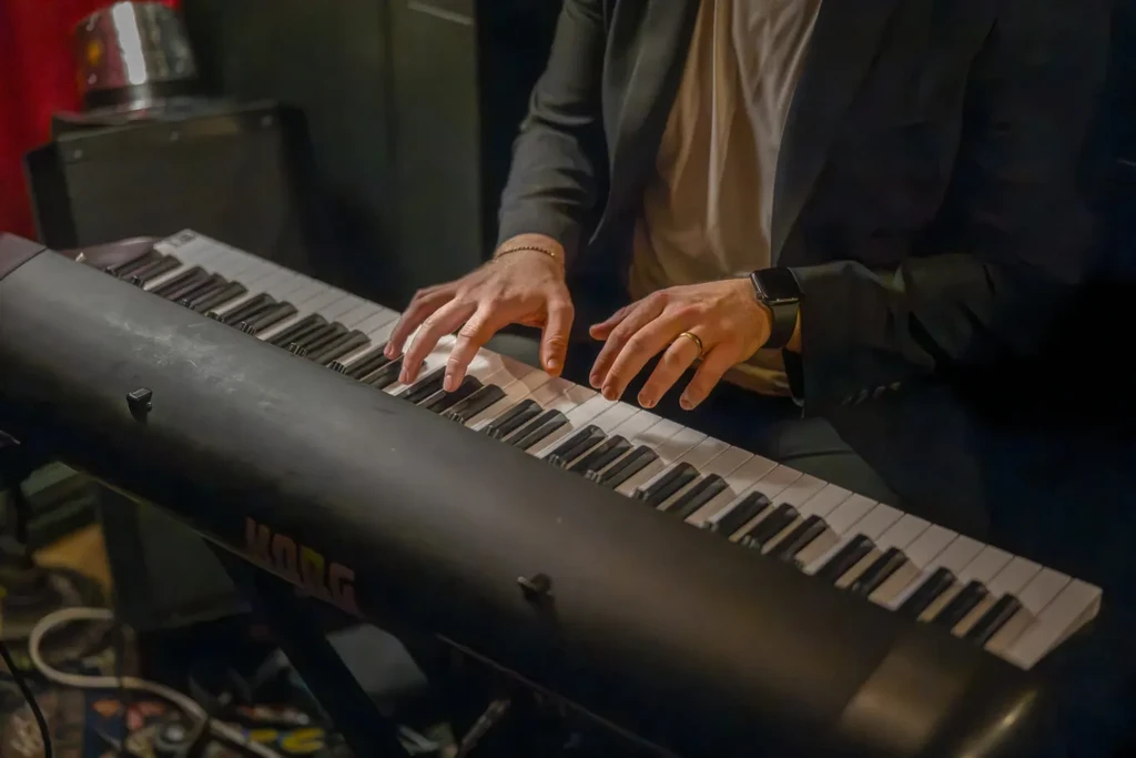 Close-up of hands playing a black Korg electronic keyboard.