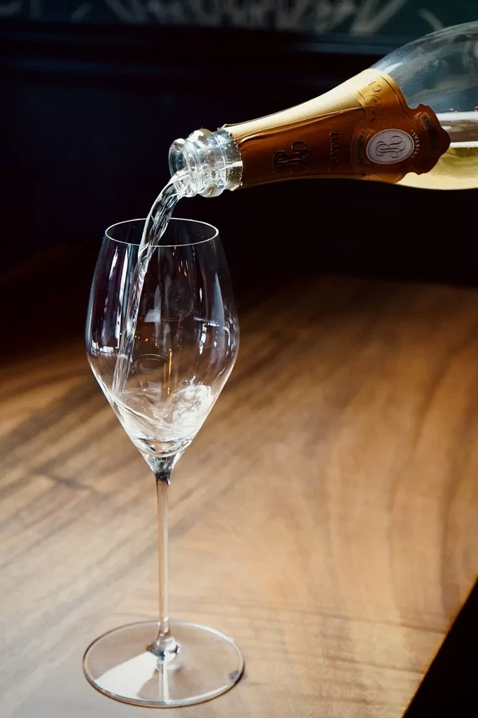 Sparkling wine pouring into tall glass, creating an effervescent splash.