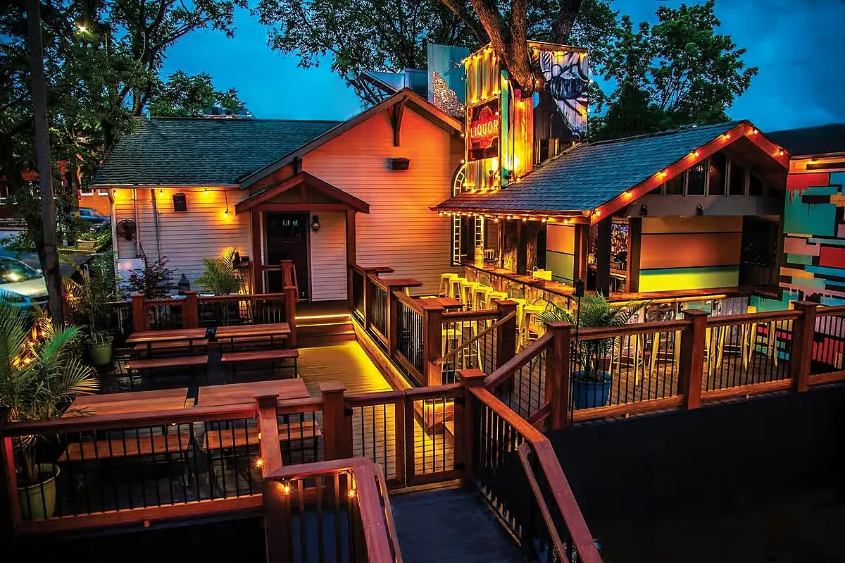 Exterior of converted house with lit deck patio seating at dusk