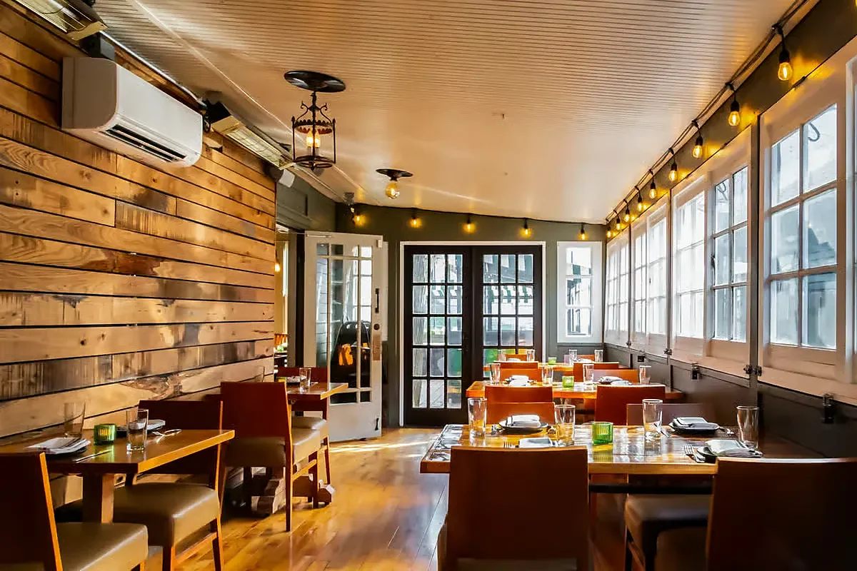 Enclosed porch dining room with wood walls, windows and string lights