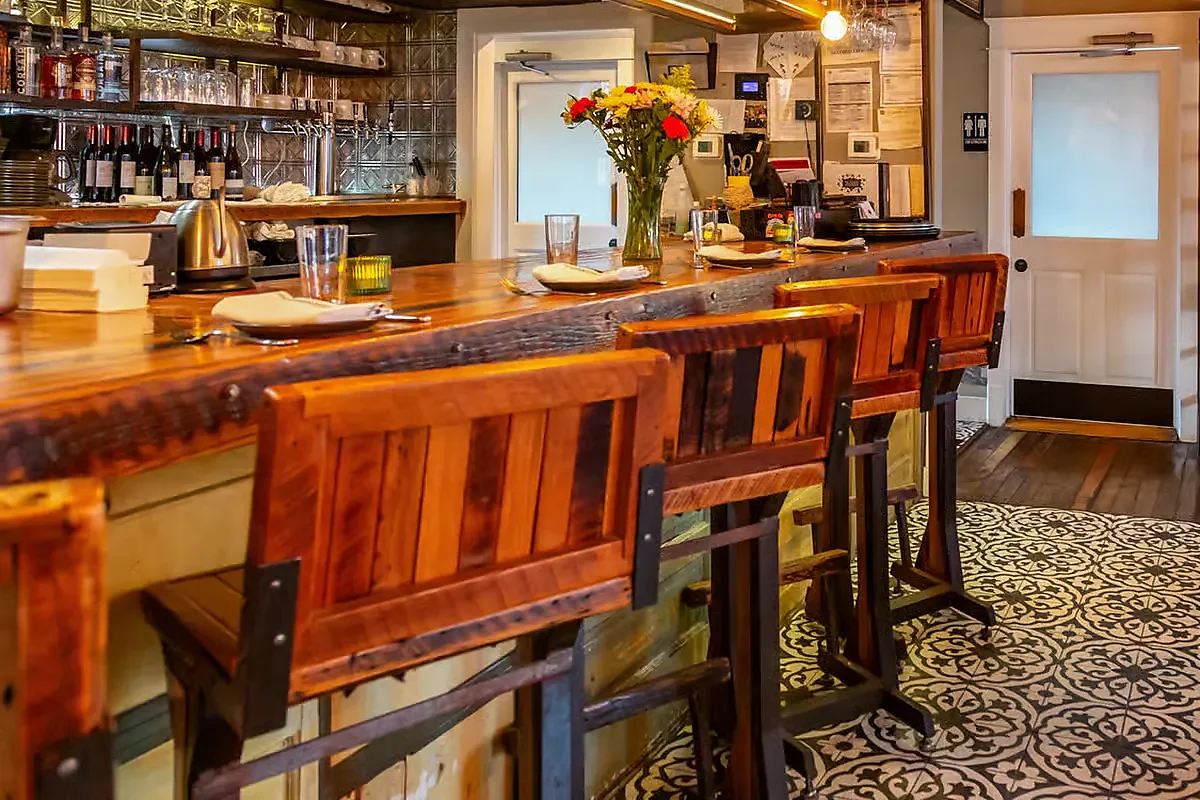 Reclaimed wood bar with stools, wine bottles and patterned tile floor