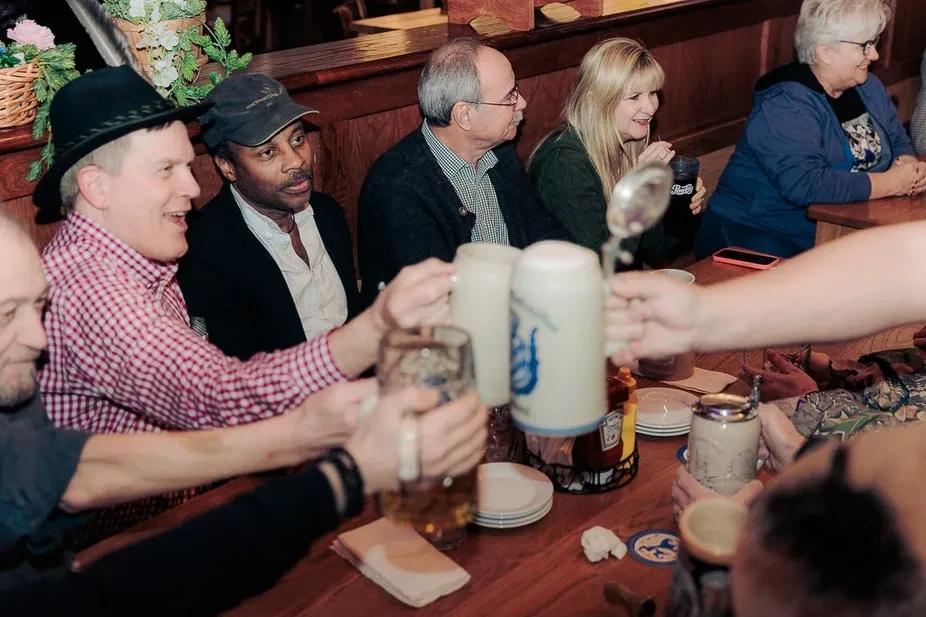 People toast with steins at a traditional restaurant table.