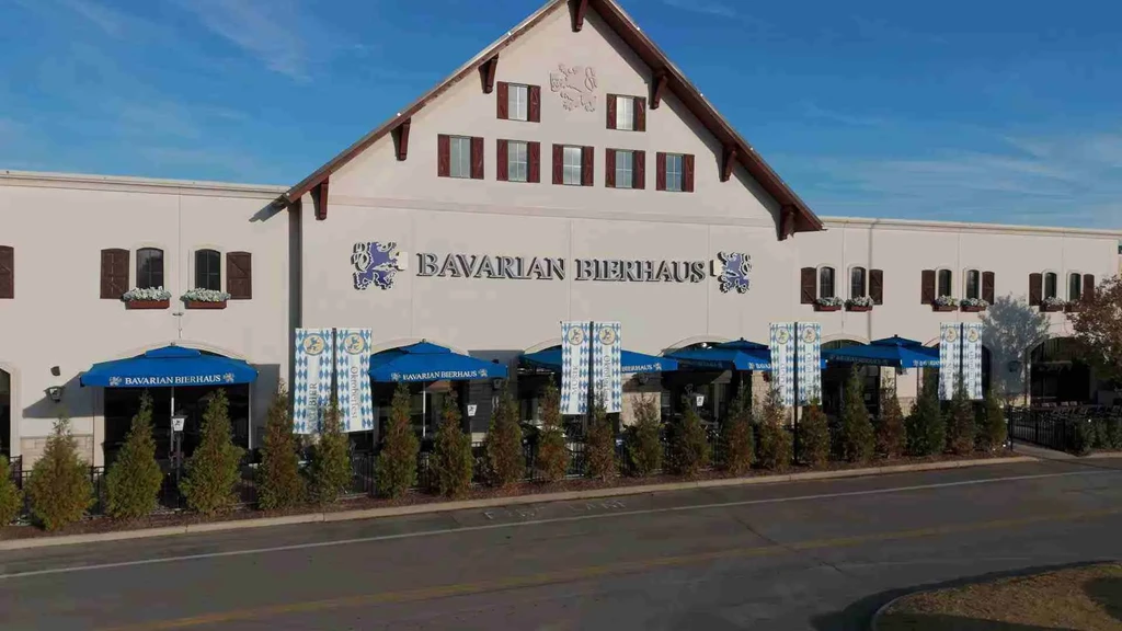 Bavarian Bierhaus exterior featuring gabled roof, patio, and blue umbrellas.