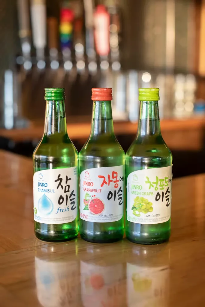 Jinro Chamisul, Grapefruit, and Green Grape soju bottles at a bar.