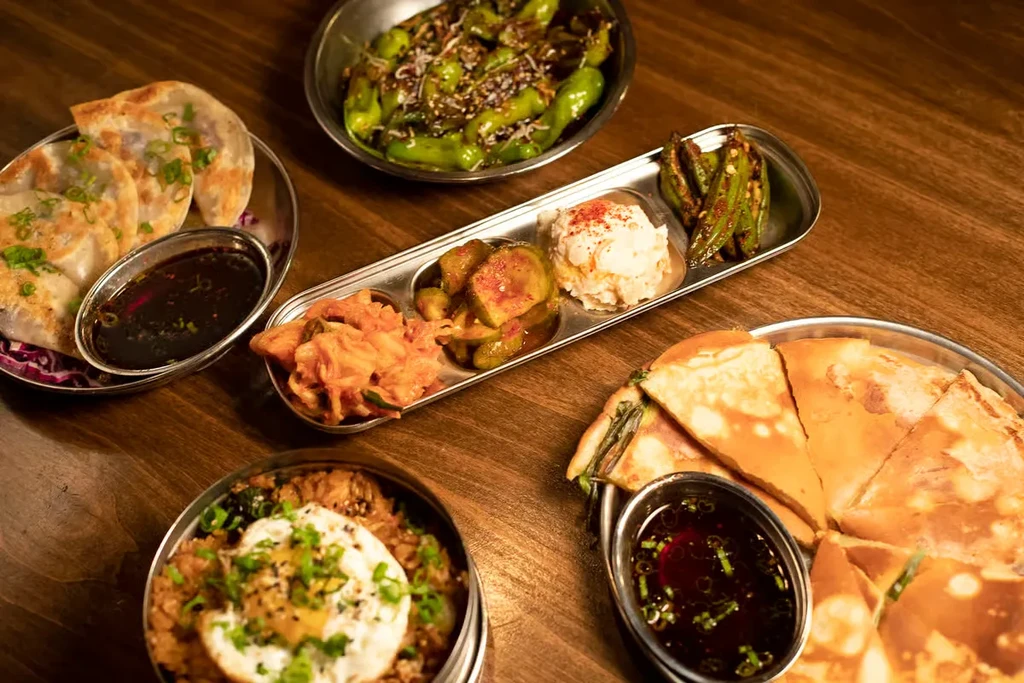 Overhead view of a wooden table laden with various Asian dishes.