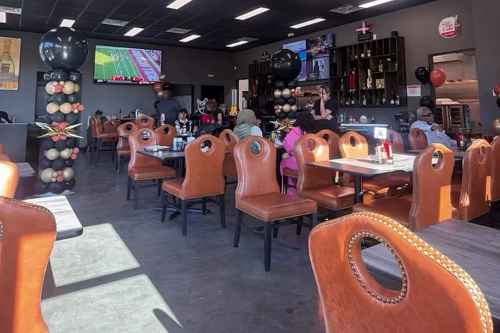 Lively, dark restaurant interior with many people and celebration balloons.