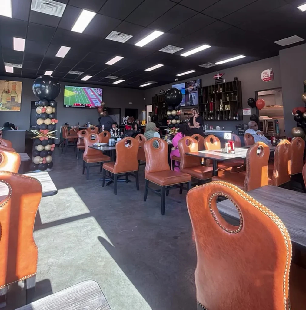 Restaurant dining area with patrons, balloon decor, and sports playing on TV.