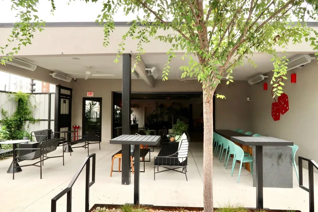 Modern outdoor restaurant patio with various seating and a prominent tree.