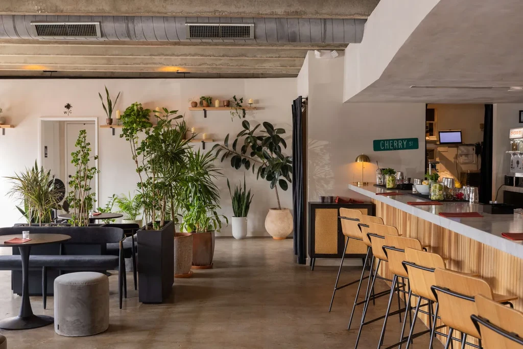 Industrial-chic restaurant bar with marble counter, wood facade, and potted plants.