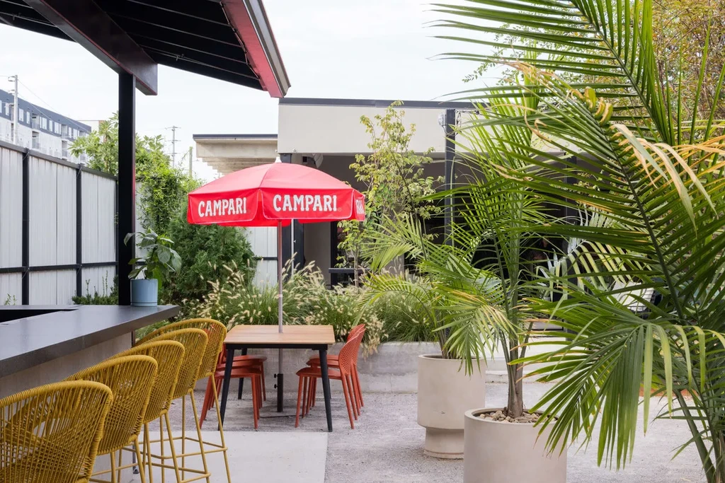 Outdoor bar patio, yellow stools, orange chairs, red Campari umbrella.