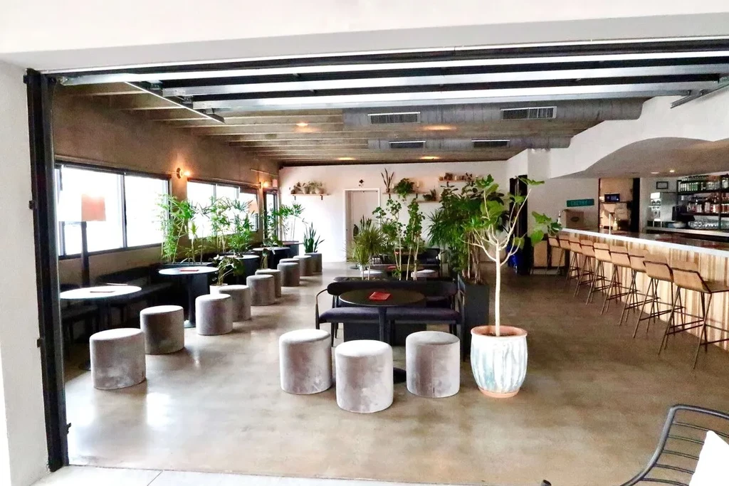 Spacious modern industrial restaurant with diverse seating, plants, bar.