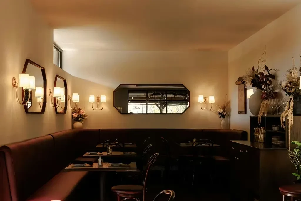 Sophisticated restaurant interior with warm lighting, booth seating, and mirrors.