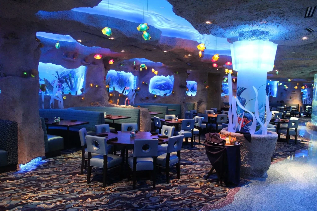 Elaborate aquatic-themed restaurant interior with blue lighting, coral decor, and fish lights.