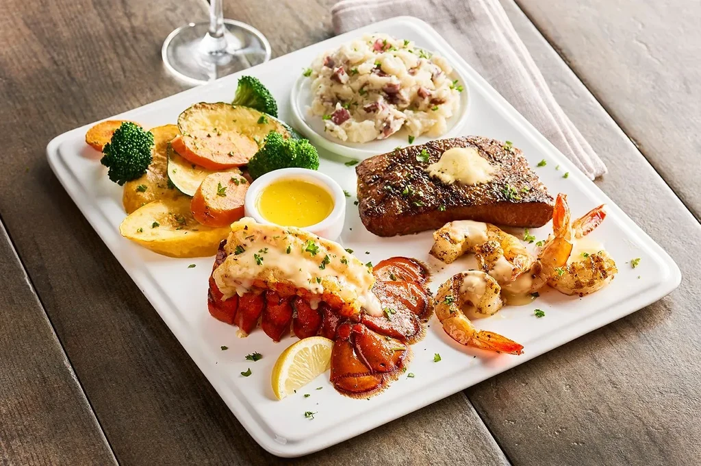 Well-arranged surf and turf: steak, lobster, shrimp, vegetables, mashed potatoes.