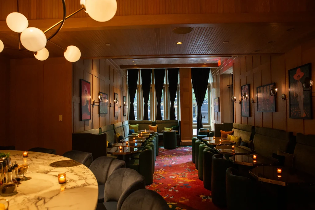 Sophisticated bar interior with marble bar, green booths, red floral carpet.